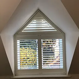 a corner window with shutters in a house