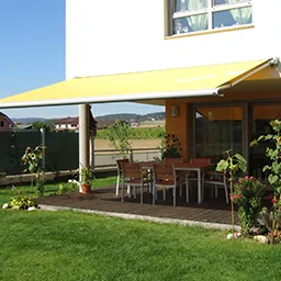a patio with a table and chairs under a yellow awning