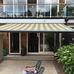 a patio covered in a yellow and blue striped awning