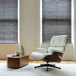 a chair and ottoman in a room with two windows